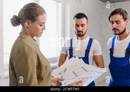 A female customer talking with the builders and considers the scheme of the house Stock Photo