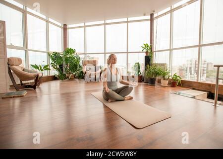 Young serene female crossing legs while practicing meditation exercise at home Stock Photo