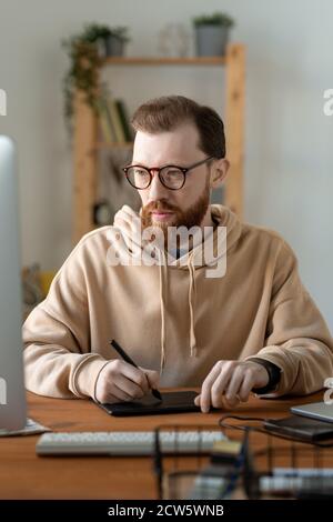 Young contemporary serious freelance designer using touchpad and stylus Stock Photo