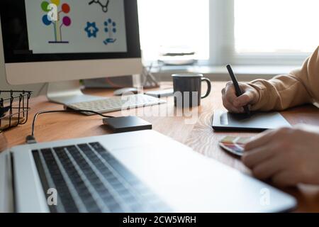 Hands of young creative freelance designer holding stylus over tablet screen Stock Photo