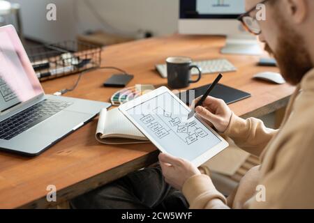 Young bearded freelance programmer holding stylus over touchscreen Stock Photo