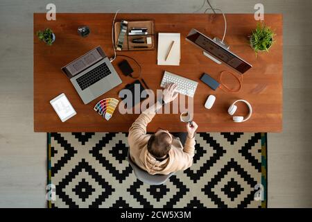 Overview of young contemporary male freelance designer using computer Stock Photo
