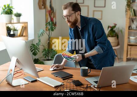 Young creative software developer or web designer bending over wooden table Stock Photo
