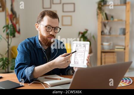 Young serious software developer pointing at sketch of smartphone model Stock Photo