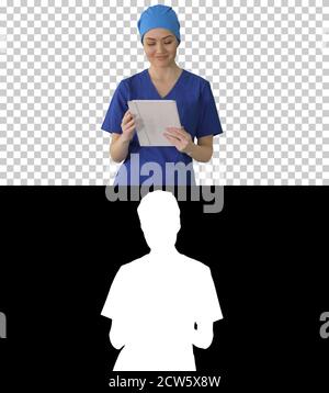 Smiling female nurse using tablet computer walking and looking a Stock Photo