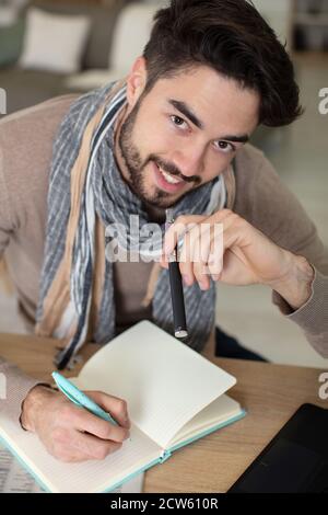 smiling young man is writing in his personal diary Stock Photo