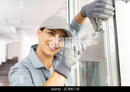 happy female builder using a screwdriver on a door Stock Photo