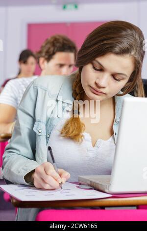 young woman with laptop and papers working in classroom Stock Photo
