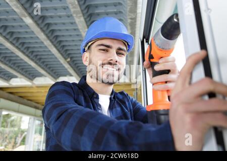 a happy man drilling window frame Stock Photo