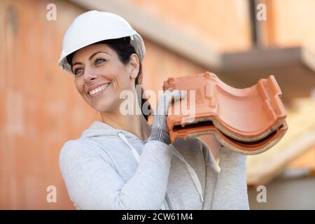 female builder holding bricks on her shoulder Stock Photo