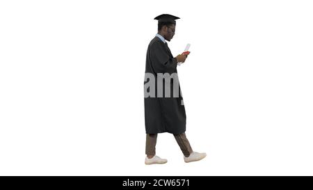 African american male student in graduation robe texting on the Stock Photo