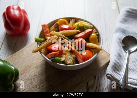 Fresh vegetable and meat saute in a bowl on a wooden platter Stock Photo