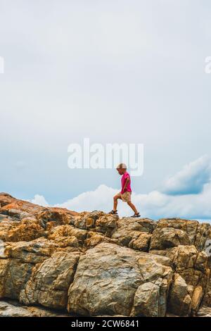 New generation will solve humanity problems. Side silhouette child boy on beautiful natural composition vivid brown stone rock shabby cliff cracks Stock Photo
