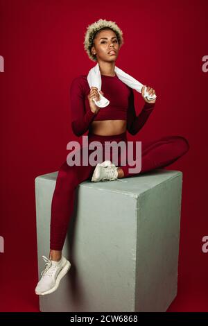 Portrait of female athlete sitting on workout box. African american fitness woman working out on exercise block. Stock Photo