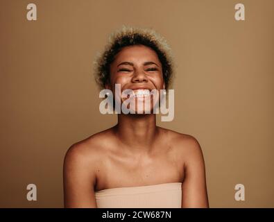 Close up of cheerful african american woman on brown background. Curly haired woman in happy mood. Stock Photo