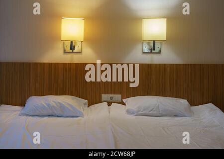 Photography of the room interior in the modern middle class hotel. Two big beds and night electric lamps. Soft beige and white colors of design. Conce Stock Photo