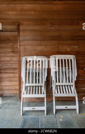 two folding wood sun chairs leaning against a wood wall Stock Photo