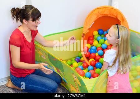 Toddler girl in child occupational therapy session doing playful exercises with her therapist. Stock Photo