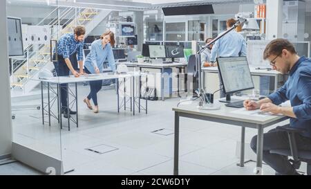 In the Busy Engineering Agency: Diverse Group of Engineers, Technicians, Working on Design for Industrial Engine Prototype. Specialists Talk During Stock Photo