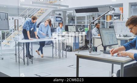 In the Busy Engineering Agency: Diverse Group of Engineers, Technicians, Working on Design for Industrial Engine Prototype. Specialists Talk During Stock Photo