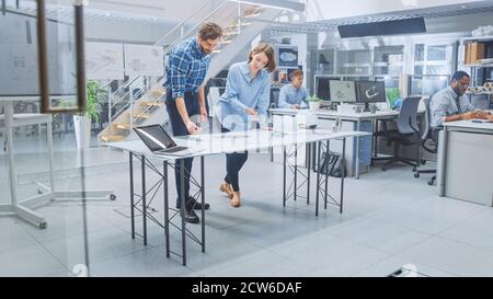 In the Busy Engineering Facility: Diverse Group of Engineers, Technicians, Working on Design for Industrial Engine Prototype. Specialists Talk During Stock Photo