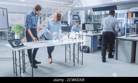 In the Busy Engineering Facility: Diverse Group of Engineers, Technicians, Working on Design for Industrial Engine Prototype. Specialists Talk During Stock Photo