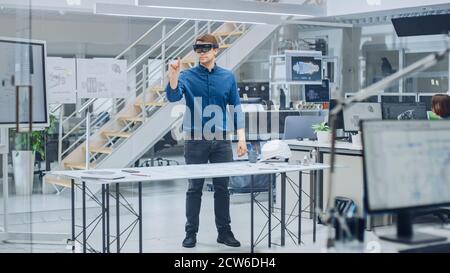 Engineering Software Developer Wearing Virtual Reality Headset Uses Gestures to Interact with Augmented Reality while Designing Industrial Engine Stock Photo
