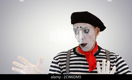Young funny mime behind an invisible wall on gradient background Stock Photo