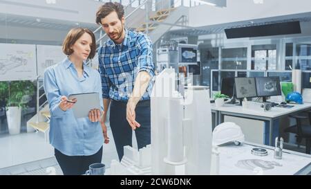 In Architectural Bureau: Architect and Engineer Talking, Using Digital Tablet Computer, Working on a Building Complex Prototype Project, Using City Stock Photo