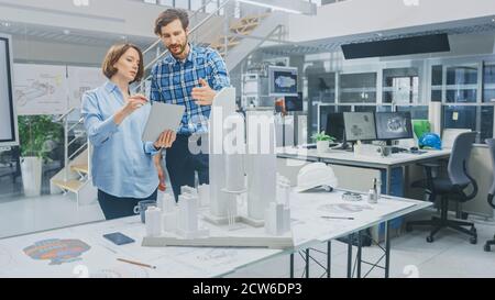 In Architectural Bureau: Architect and Engineer Talking, Using Digital Tablet Computer, Working on a Building Complex Prototype Project, Using City Stock Photo
