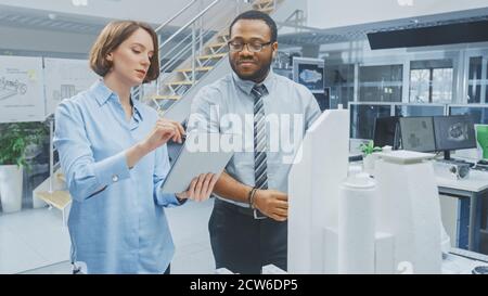 In Architectural Bureau: Architect and Engineer Talking, Working on a Building Complex Prototype Project, Using City Model and Computers Running 3D Stock Photo