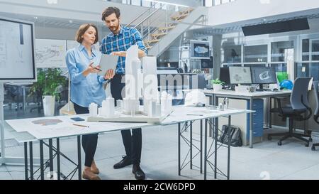 In Architectural Bureau: Architect and Engineer Talking, Using Digital Tablet Computer, Working on a Building Complex Prototype Project, Using City Stock Photo