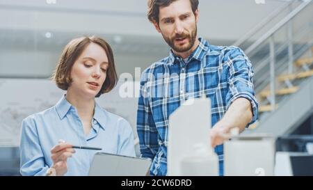In Architectural Bureau: Young Professional Female Architect and Experienced Male Chief Engineer Talking, Using Digital Tablet Computer, Working on Stock Photo