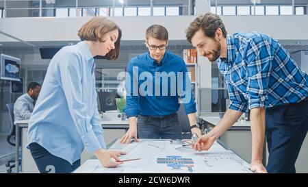In the Industrial Engineering Facility: Female Designer Works with Industrial Engineer and Master Technician, They have Discussion, Analyse Engine Stock Photo