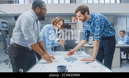 In the Industrial Engineering Facility: Female Designer Works with Industrial Engineer and Master Technician, They have Discussion, Analyse Engine Stock Photo