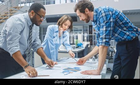 In the Industrial Engineering Facility: Female Designer Works with Industrial Engineer and Master Technician, They have Discussion, Analyse Engine Stock Photo