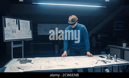Software Development Engineer Wearing Virtual Reality Headset Gestures and Manipulates Components in Augmented Reality. Engineering Facility Has Desk Stock Photo