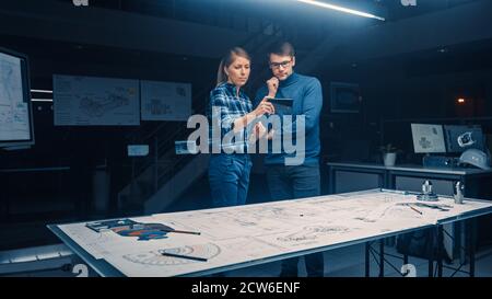 Two Young Software Development Engineers Talk and Use Smartphone with Augmented Reality for Reading and Interacting with Car and Engine Concept Stock Photo