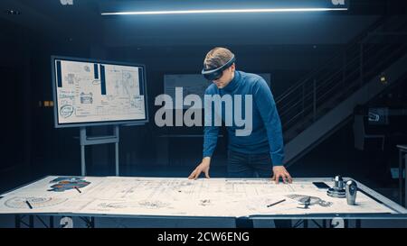 Software Development Engineer Wearing Virtual Reality Headset Gestures and Manipulates Components in Augmented Reality. Engineering Facility Has Desk Stock Photo