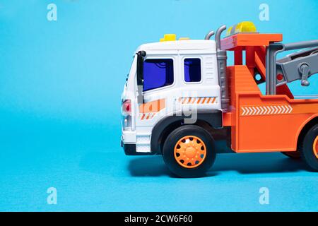 Toy orange tow truck on blue background banner with space for text. Children's car for loading and transporting cars Stock Photo