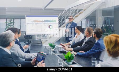 In Corporate Meeting Room: Creative Director Uses Digital Interactive Whiteboard for Presentation to Board of Executives, Lawyers, Investors Stock Photo