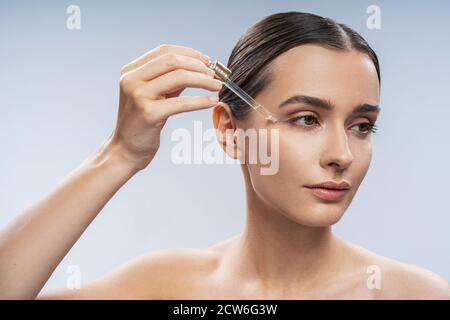Young beautiful woman applying nature oil under eyes Stock Photo