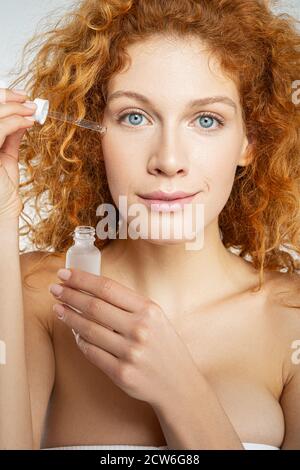 Woman putting cream on her face under eyes Stock Photo