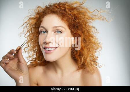 Young woman using pliers on her eyebrow Stock Photo