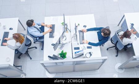 In the Bright Busy Office Rows of Diverse Professionals Working on Desktop Computers, Talking, Doing Client Support, Communicating with Customers Stock Photo