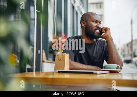 Contented man enjoying pleasant phone talk in the city