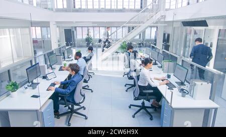 Diverse Team of Business Managers and Specialists Work on Desktop Computers with Two Rows of Tables Side by Side. Young and Motivated Business people Stock Photo
