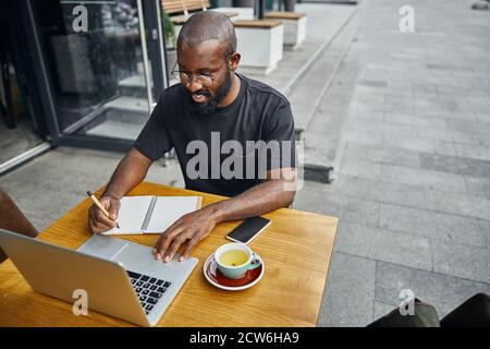 Clever young specialist enjoying working outdoors on the laptop Stock Photo
