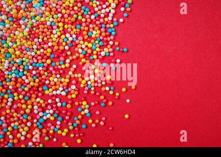 Sugar sprinkle dots, decoration for cake and bakery, on red background.Festive Christmas background Stock Photo