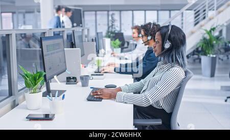 Team of Handsome and Beautiful Diverse Multicultural Customer Service Operators Working at a Busy Modern Call Center with Specialists Wearing Headsets Stock Photo